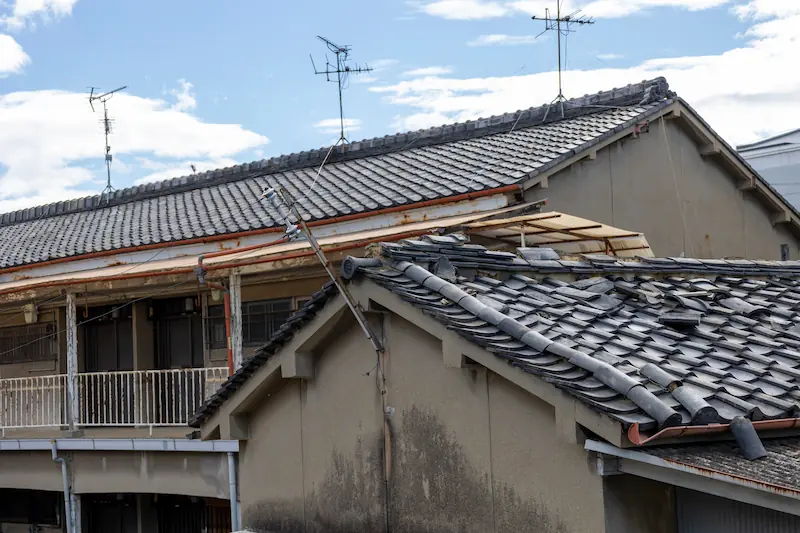瓦屋根が壊れた古い長屋、修繕や建て替えが必要な住宅